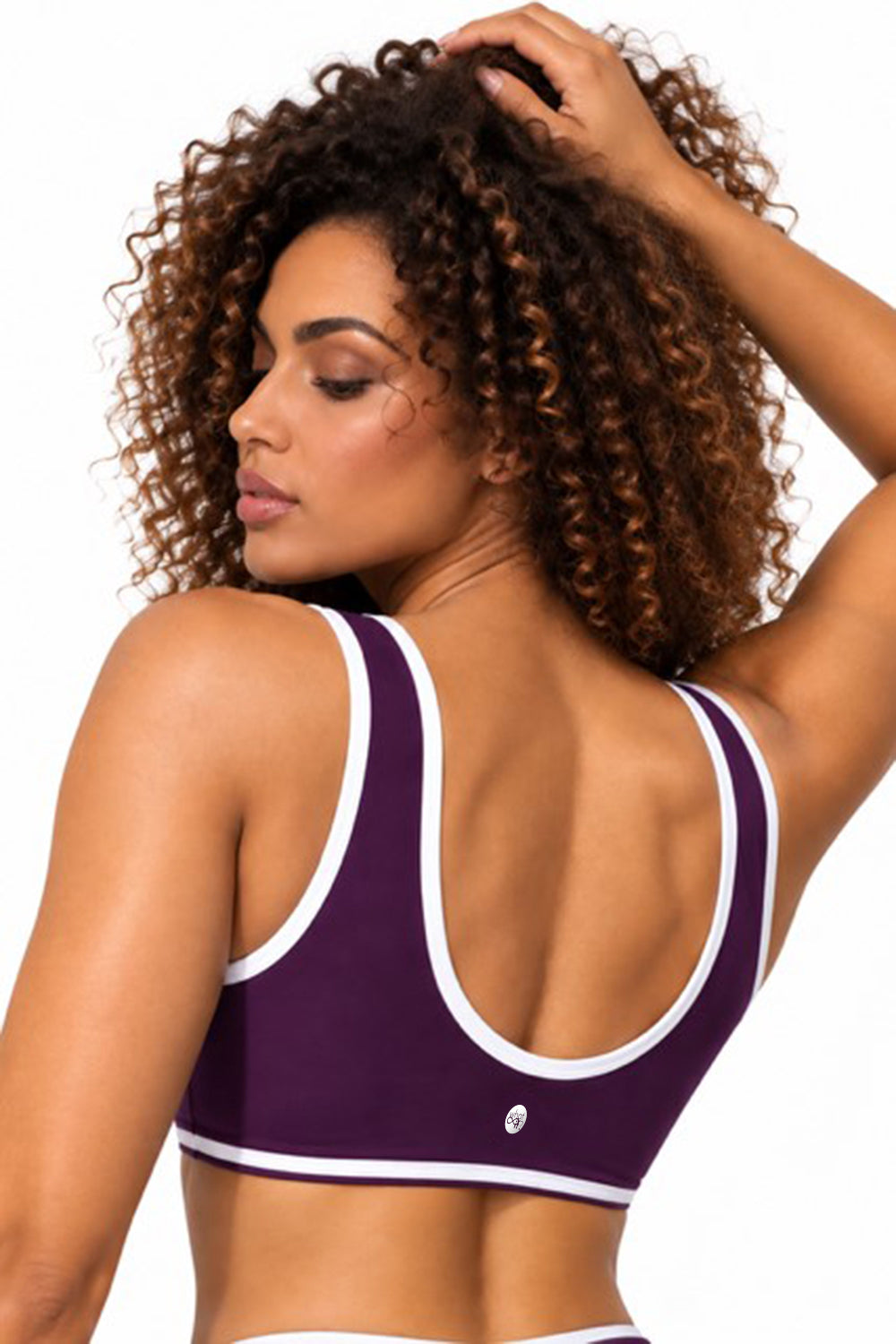Purple sports bra with white trim worn by a model, back view